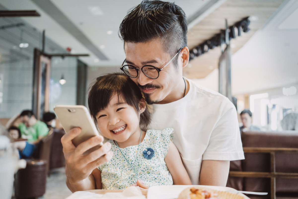 Dad and daughter looking at phone together